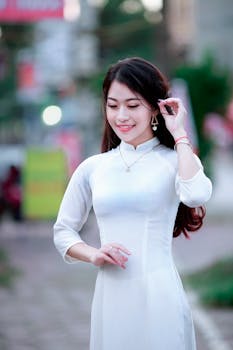 pexels photo 899757 899757 A woman in a white Ao Dai poses gracefully outdoors, showcasing traditional Vietnamese fashion.